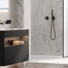 Ein modernes Badezimmer mit einem eleganten schwarzen Waschbecken und einer stilvollen Dusche aus Glas und Marmor.